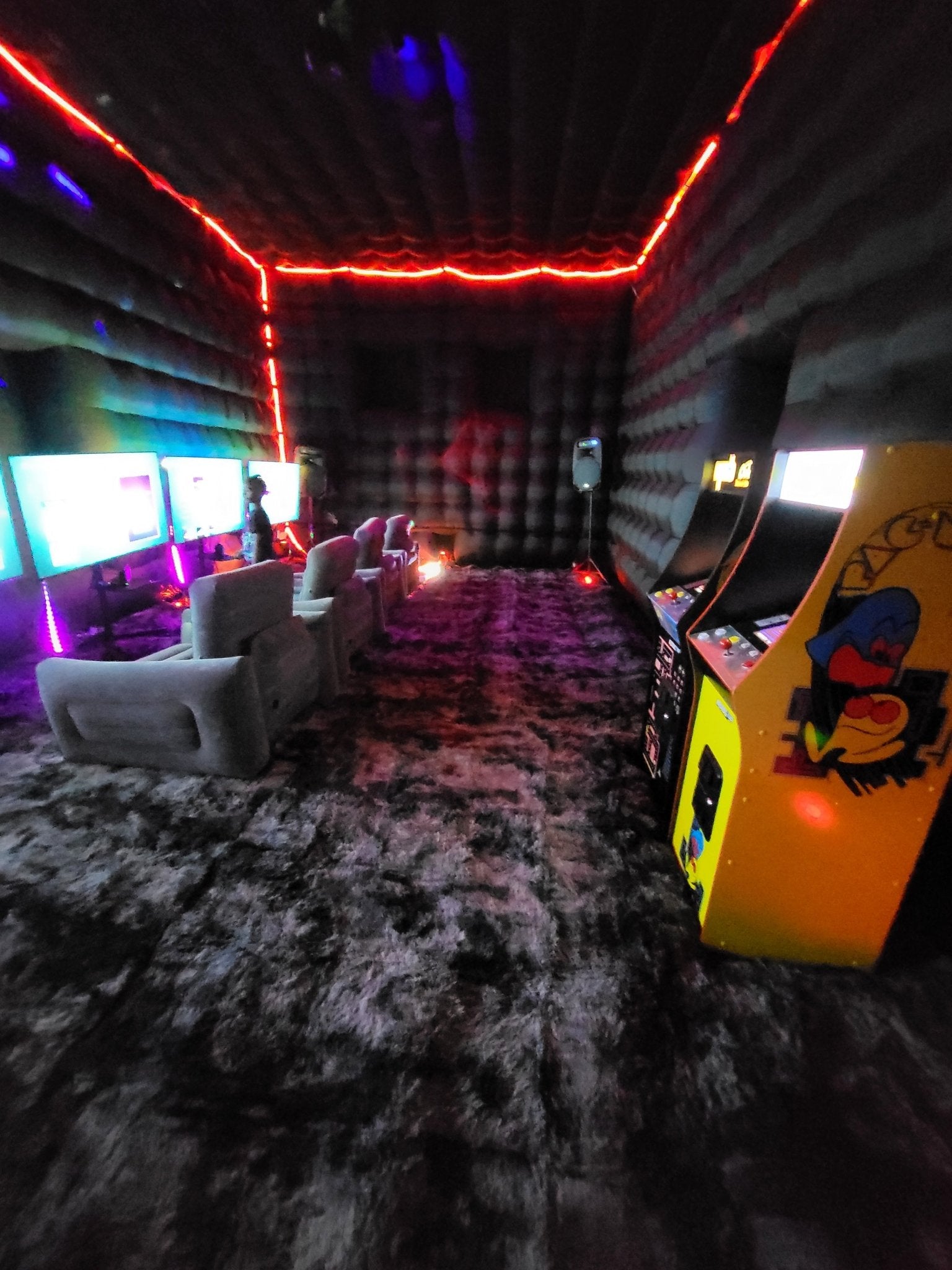 Inflatable indoor gaming club with carpeted floor, inflatable chairs, multiple TV screens, PlayStation and Nintendo Switch consoles for group play